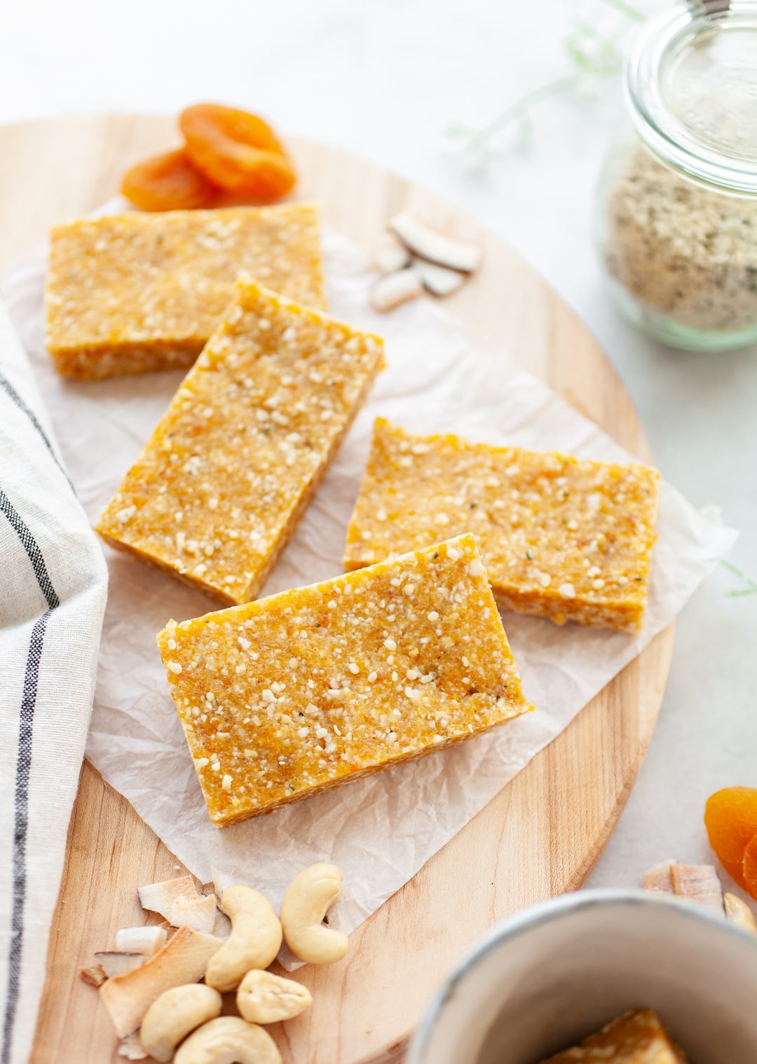 Apricot Cashew Energy Bars on a wood board with apricots