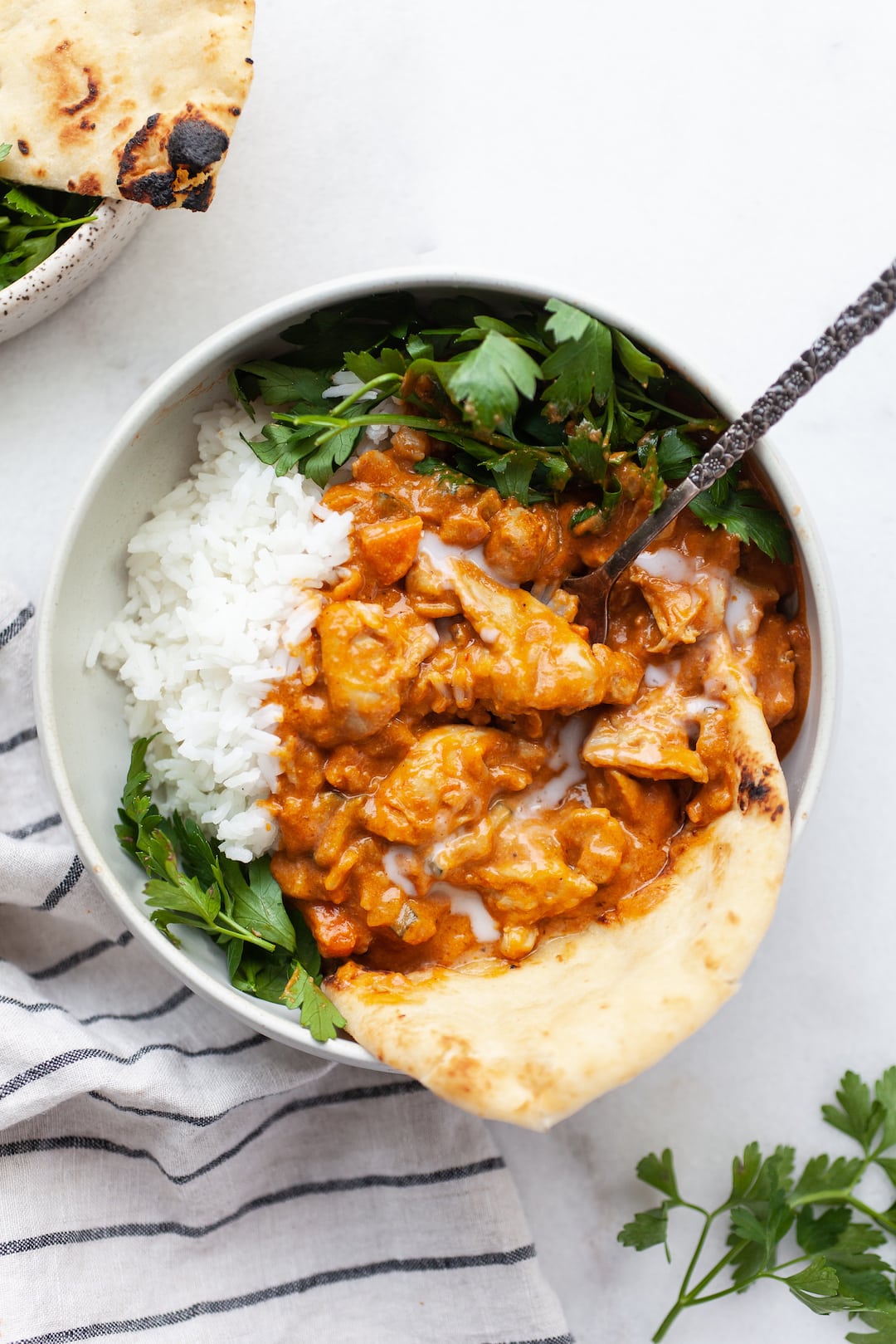 Bowl of dairy free butter chicken with naan, rice, and parsley