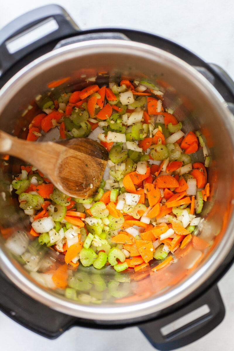 image of the inside of an instant pot with carrots, celery, and onion