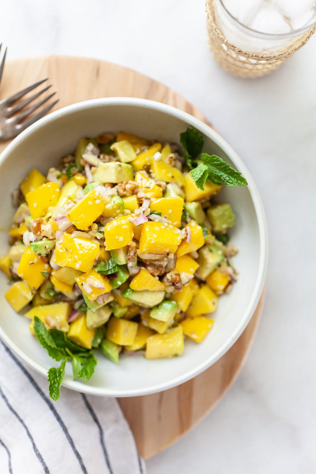 overhead view of Easy Mango Avocado Salad in a bowl with mint, mango, avocado, and red onion