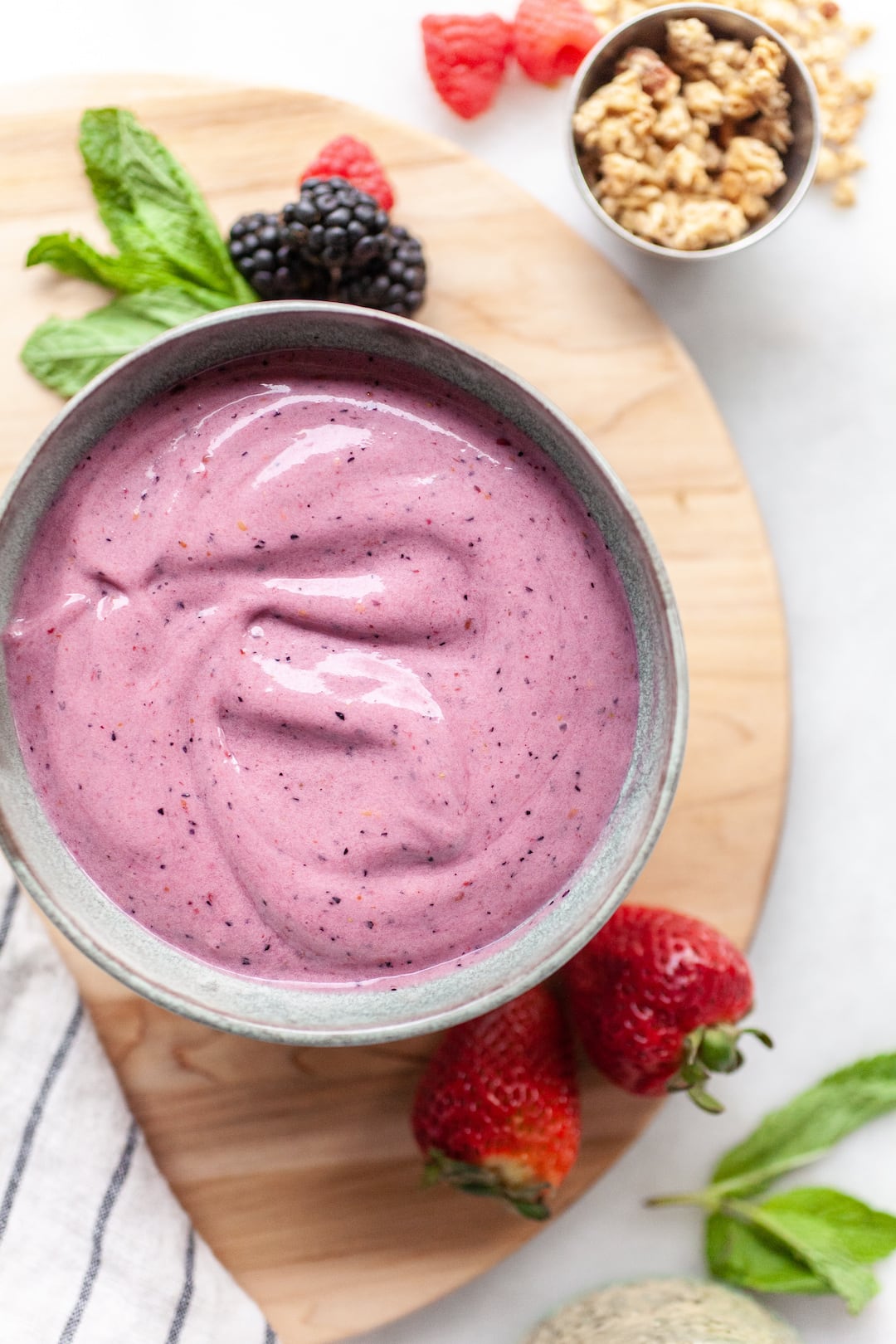 a berry smoothie bowl that's pin with fresh berries on the side