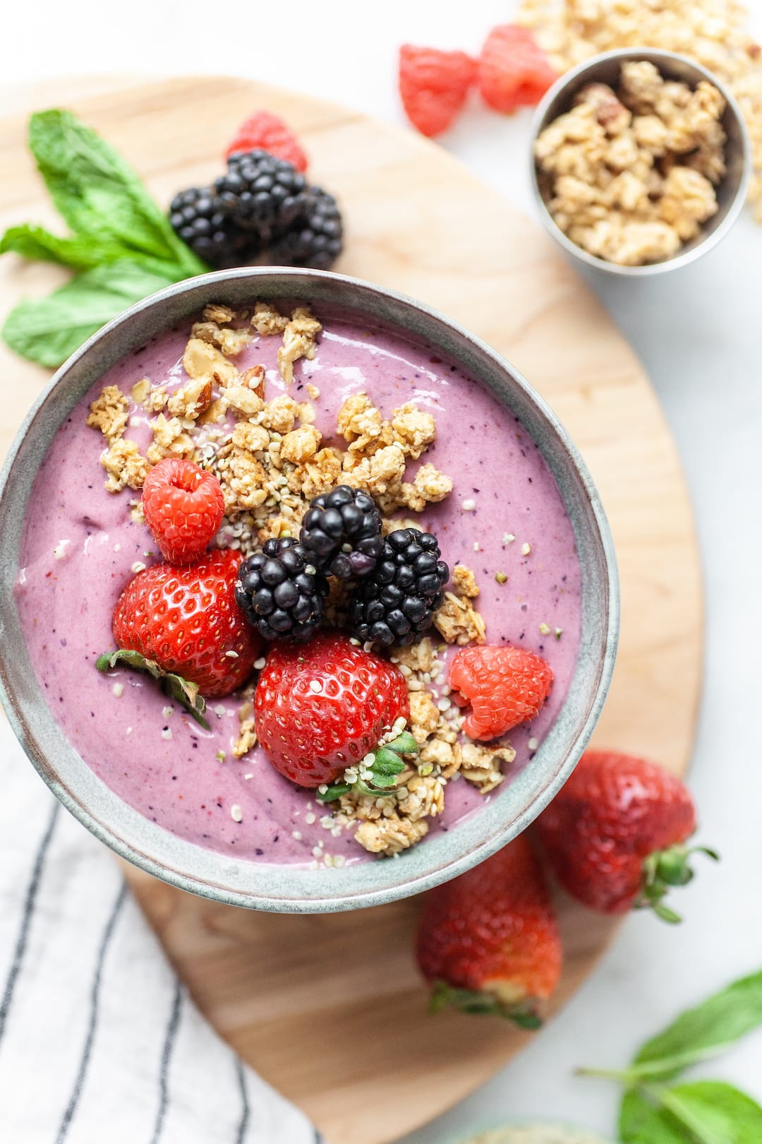 bowl with berry smoothie topped with strawberries, blackberries, and granola, and hemp seeds