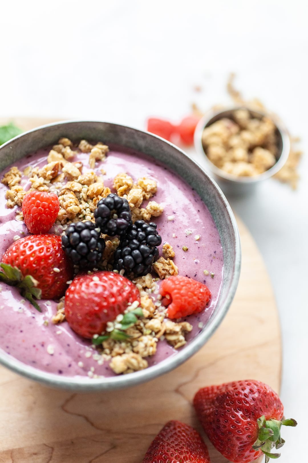 berry smoothie bowl topped with granola, strawberries, and blackberries