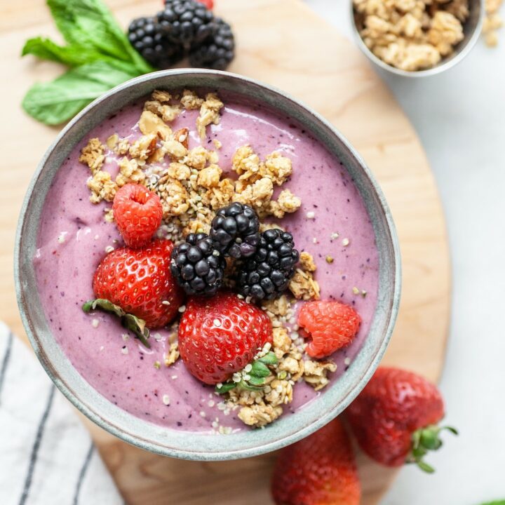 bowl with berry smoothie topped with strawberries, blackberries, and granola