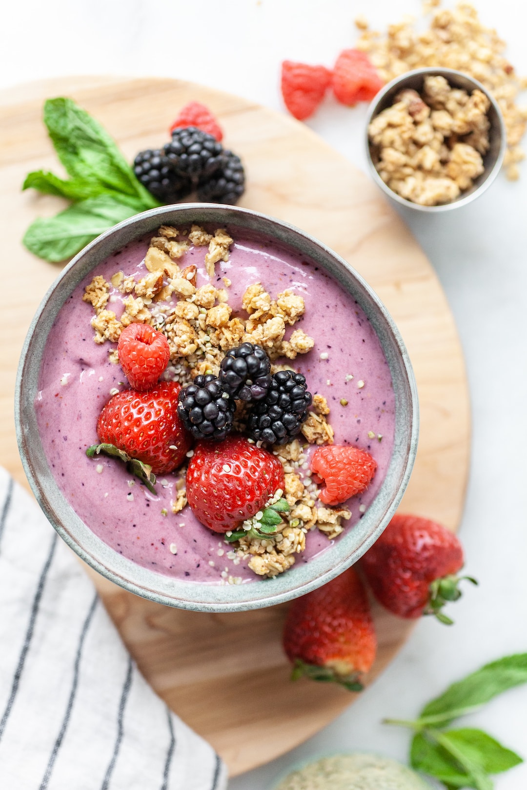 bowl with berry smoothie topped with strawberries, blackberries, and granola 