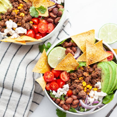 This delicious and easy healthy taco salad recipe is made with a simple salsa dressing, extra lean ground beef, veggies galore, corn, beans, dairy free cheese and quick baked tortilla chips. It’s a clean eating recipe that is perfect for meal prep and a filling lunch or dinner!