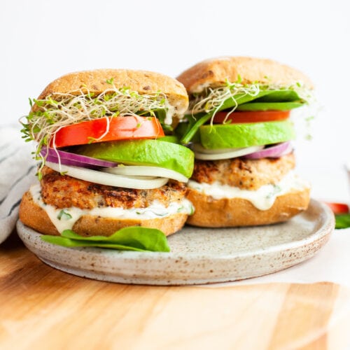 two turkey burgers with tomato, sprouts avocado, and onion