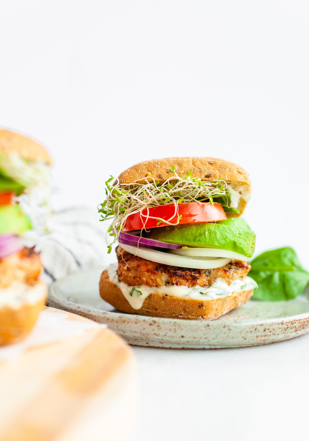 turkey burgers stacked with avocado, tomato, and sprouts on a grain bun
