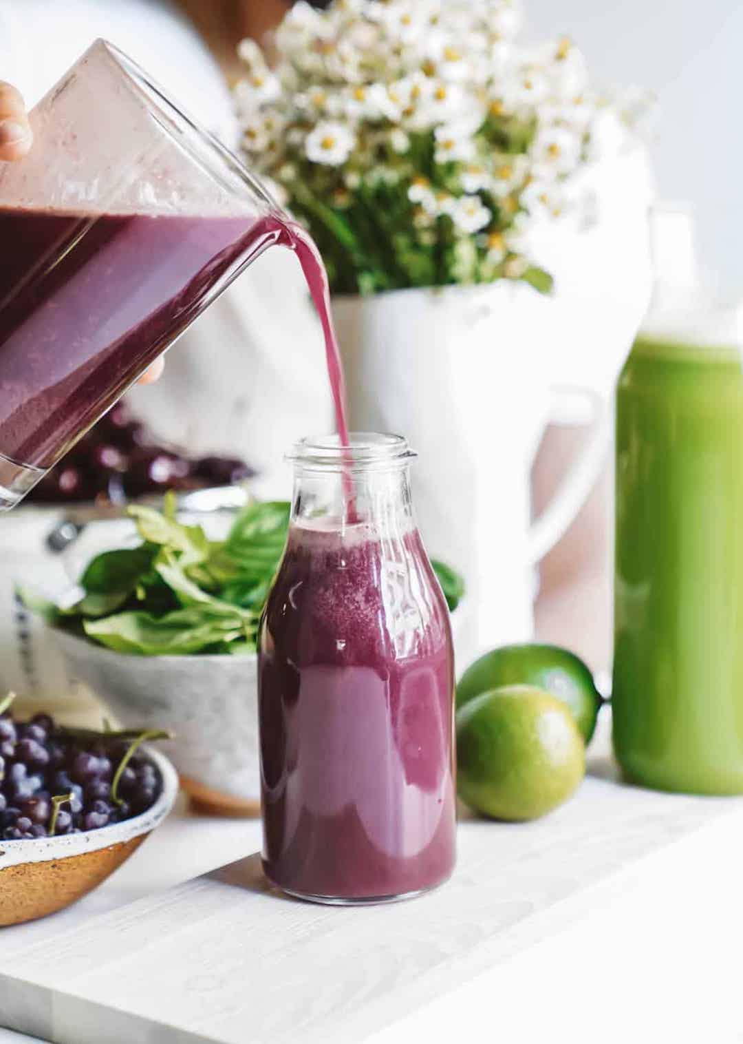 Pouring purple juice from a pitcher into a jar
