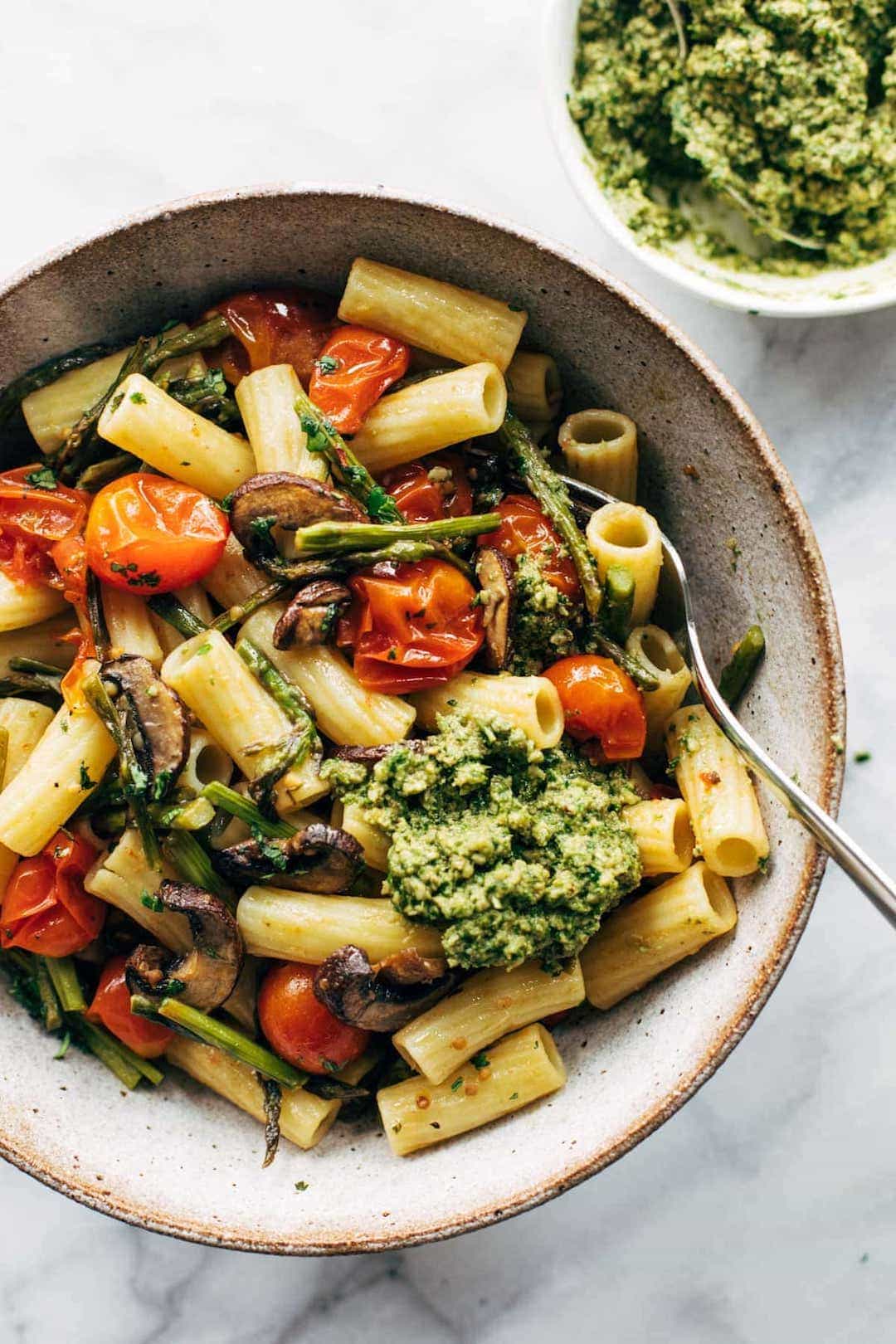 pasta salad in a bowl with tomatoes and pesto