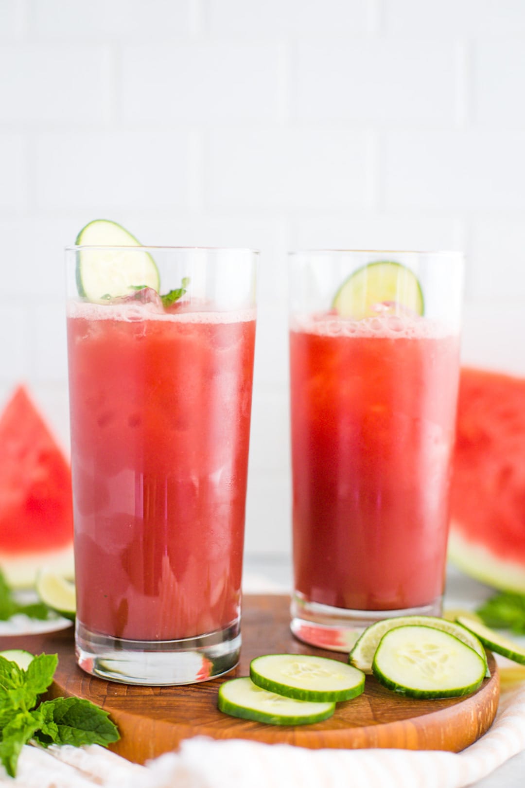 Two large glasses of watermelon juice with lime wedges