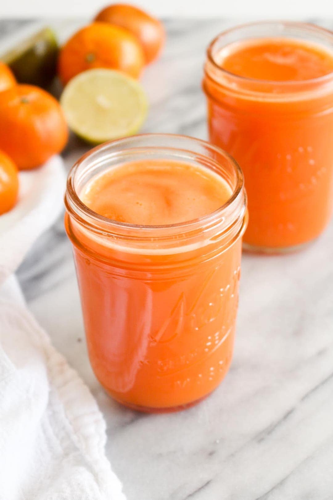 Bright orange juice in a jar on a marble platter