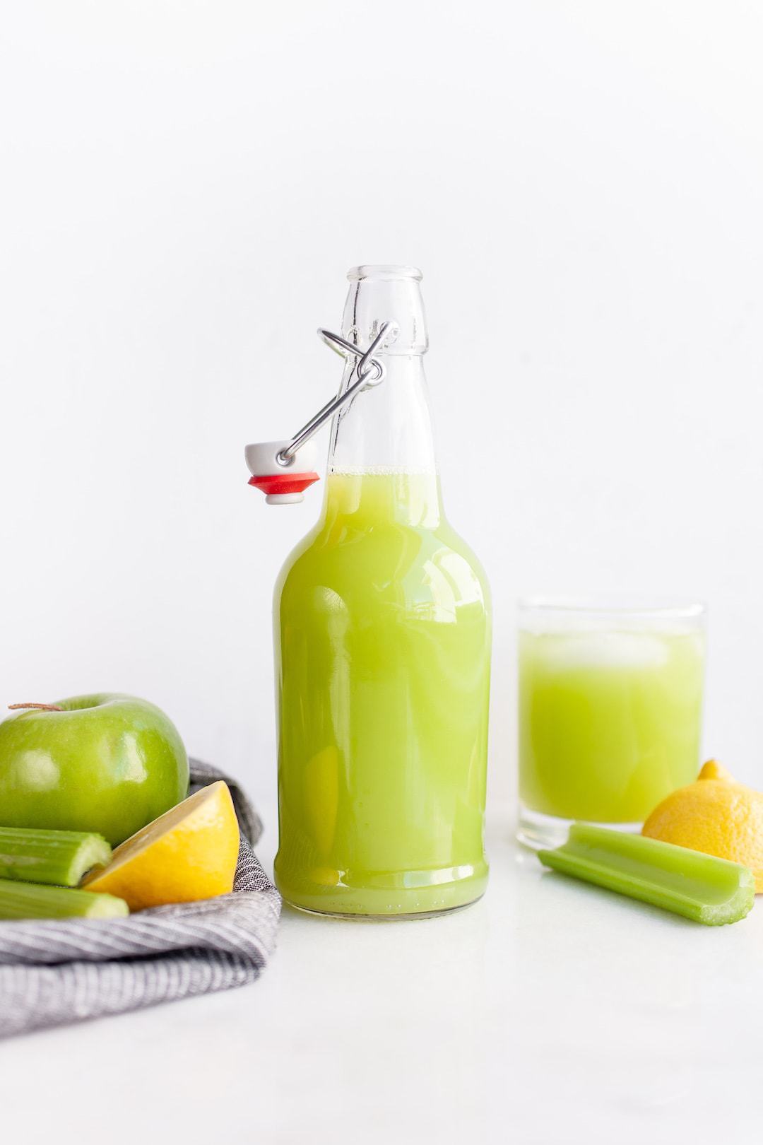 Jar of green celery juice with apples and celery on the side