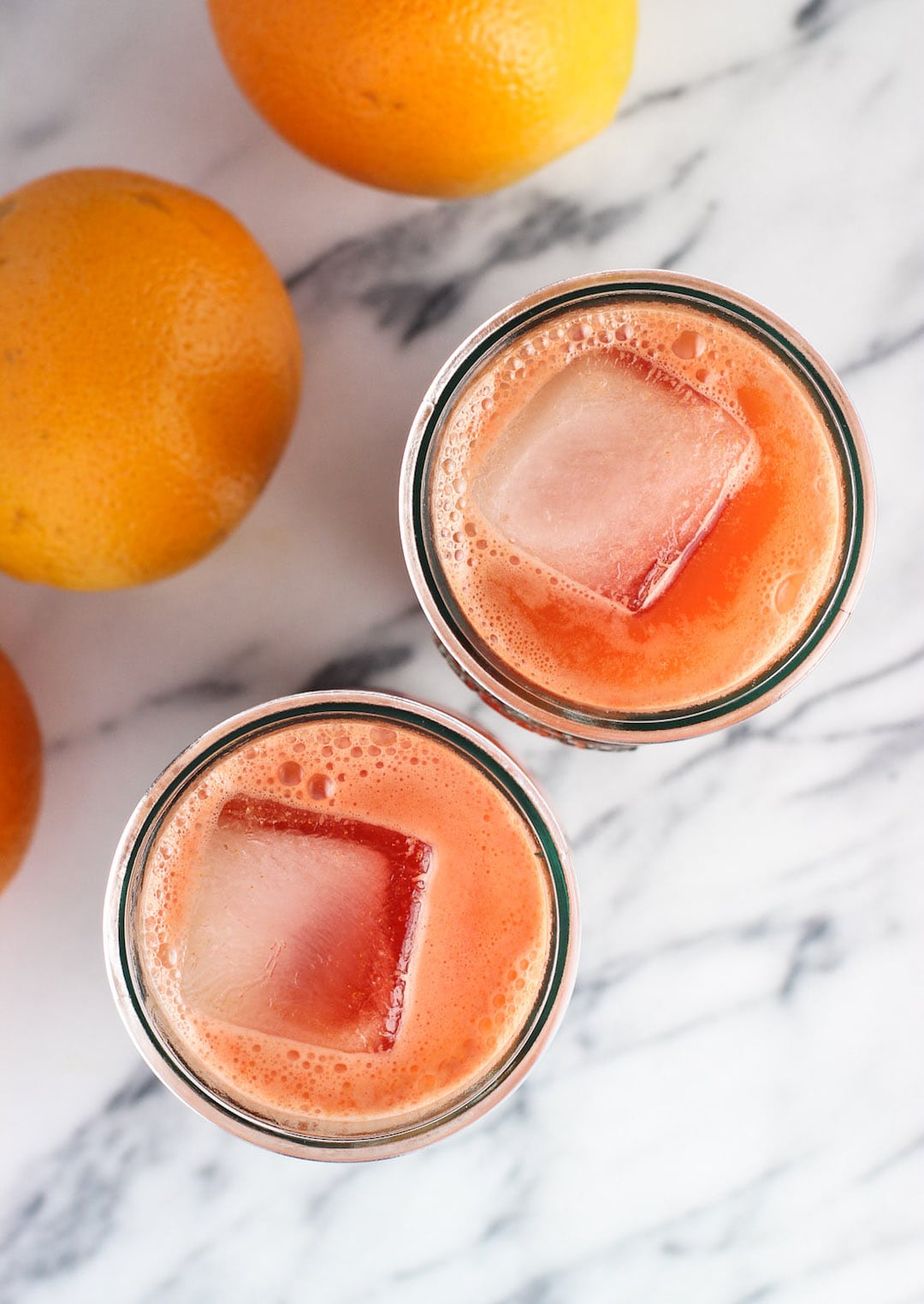Orange carrot juice in two glasses with ice cubes