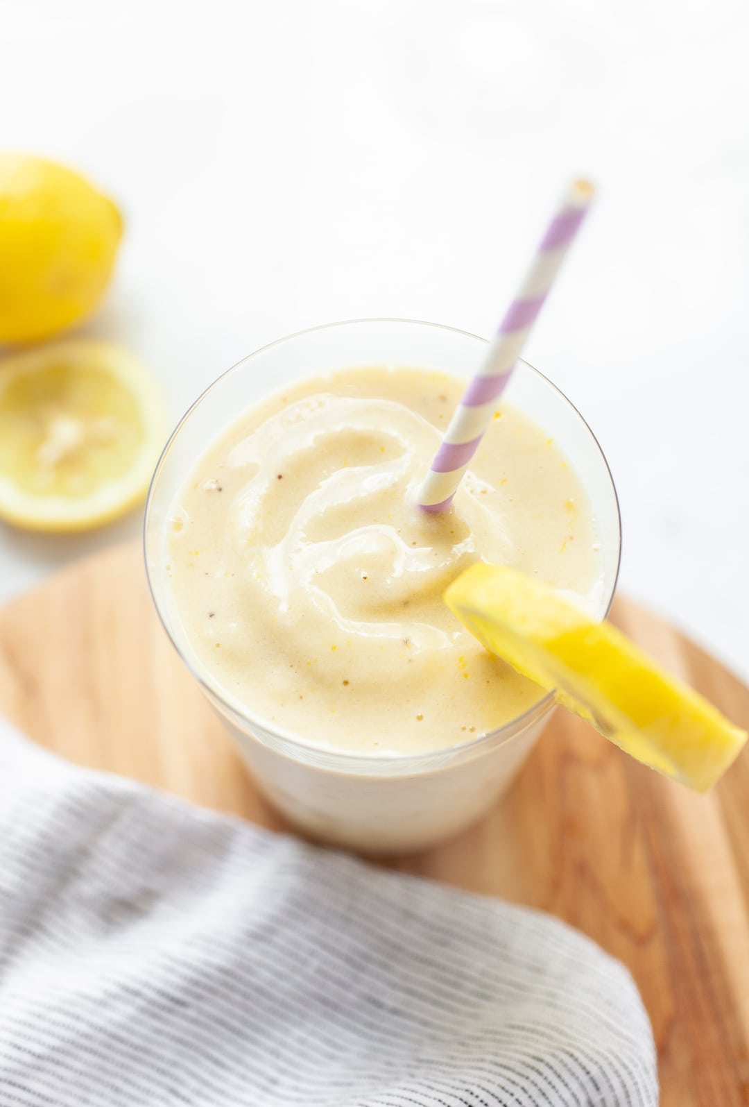 glass of lemon banana peach smoothie with purple straw