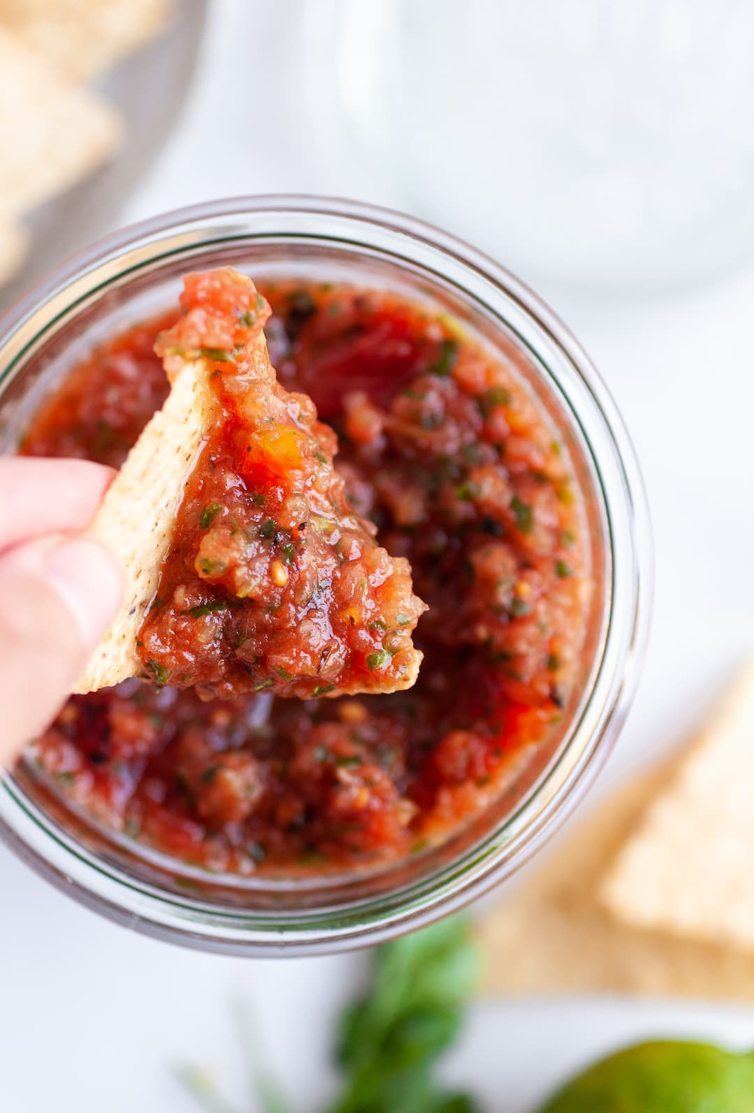 scoop of homemade salsa from a jar with a tortilla chip