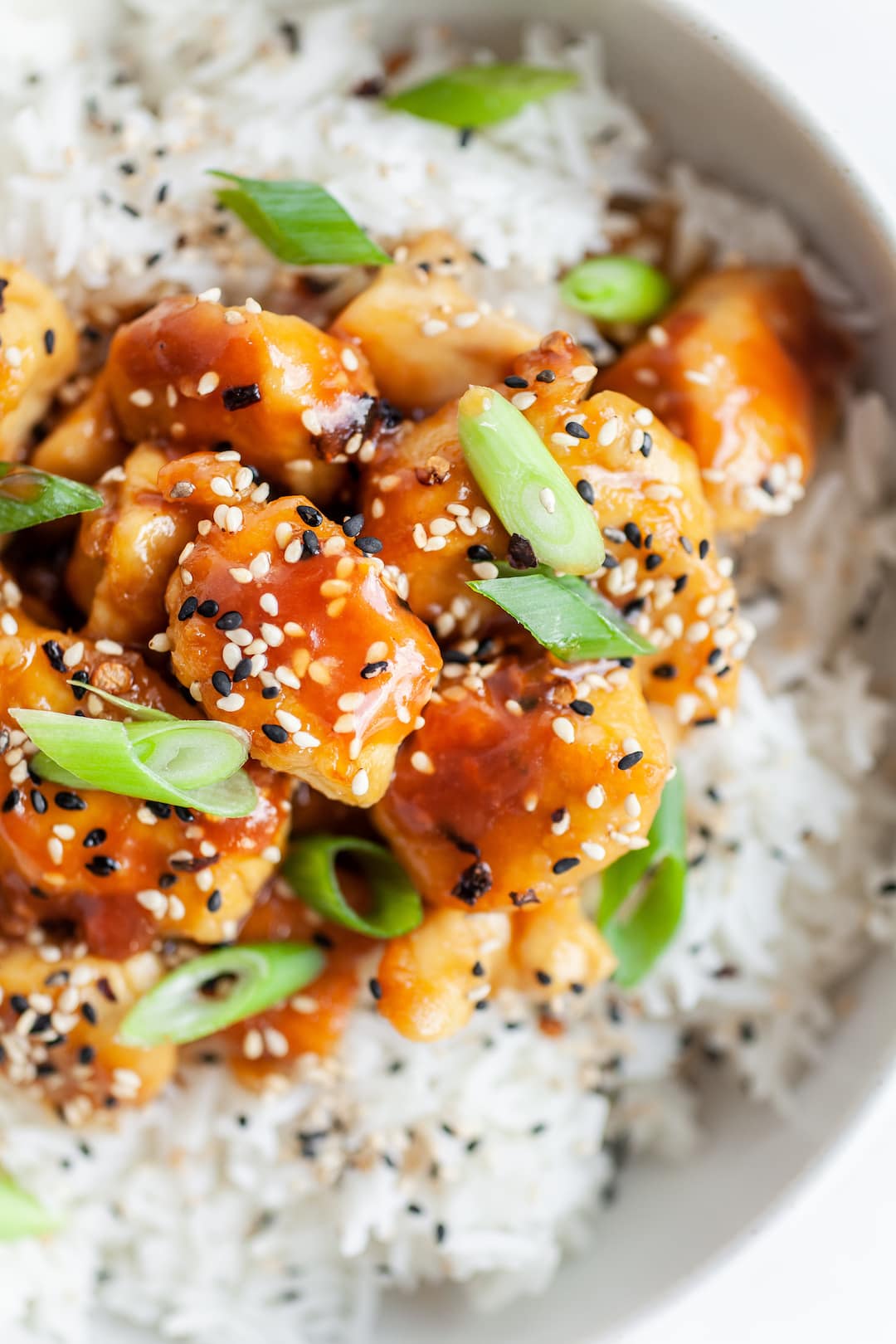 close up of orange chicken with sesame seeds and green onion