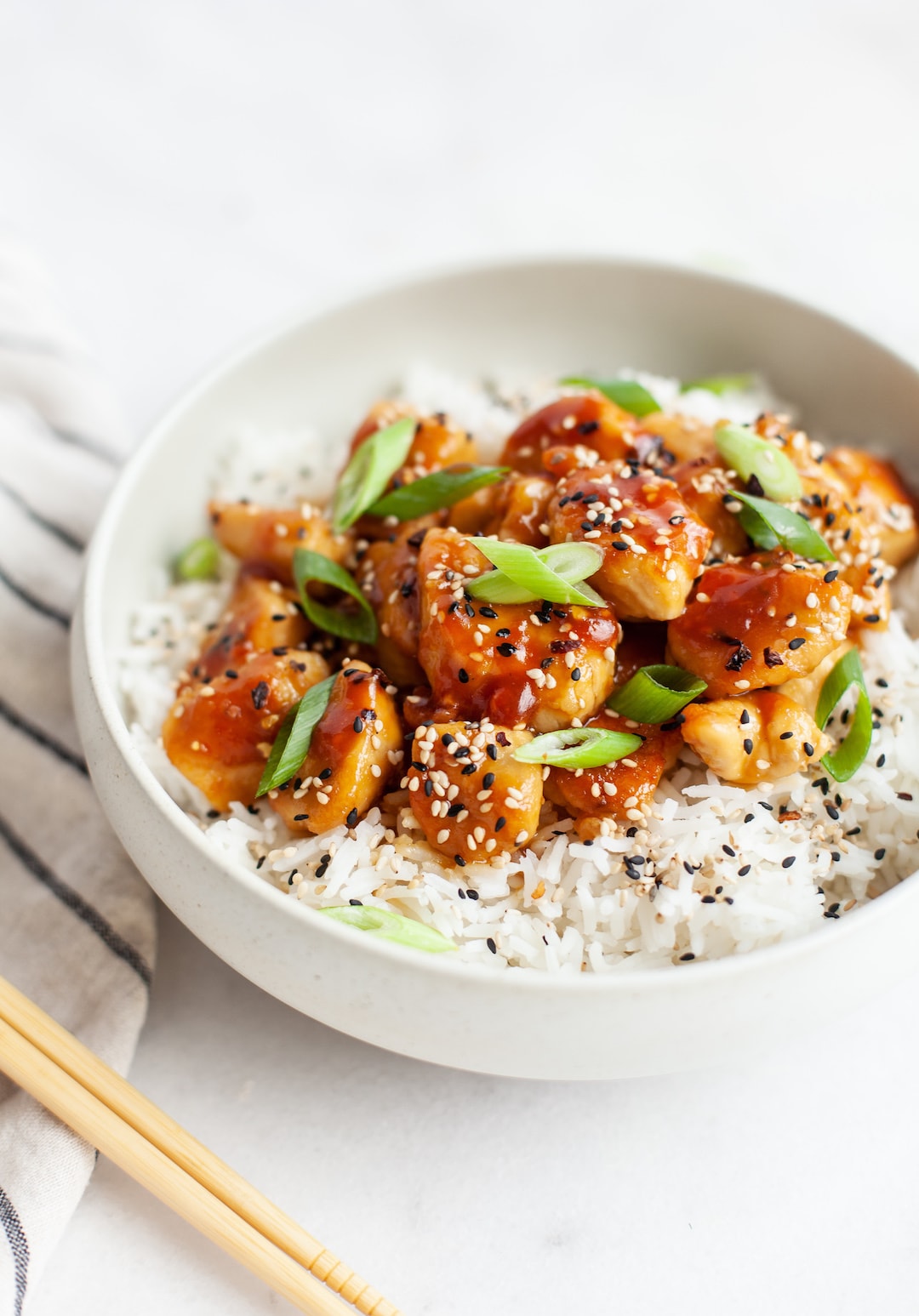 healthy orange chicken in a white bowl with rice