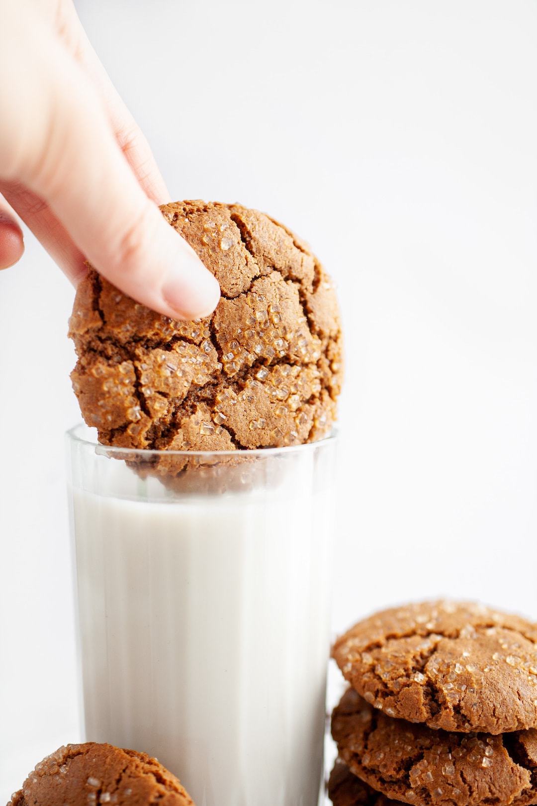 dipping ginger molasses cookie into a glass of milk