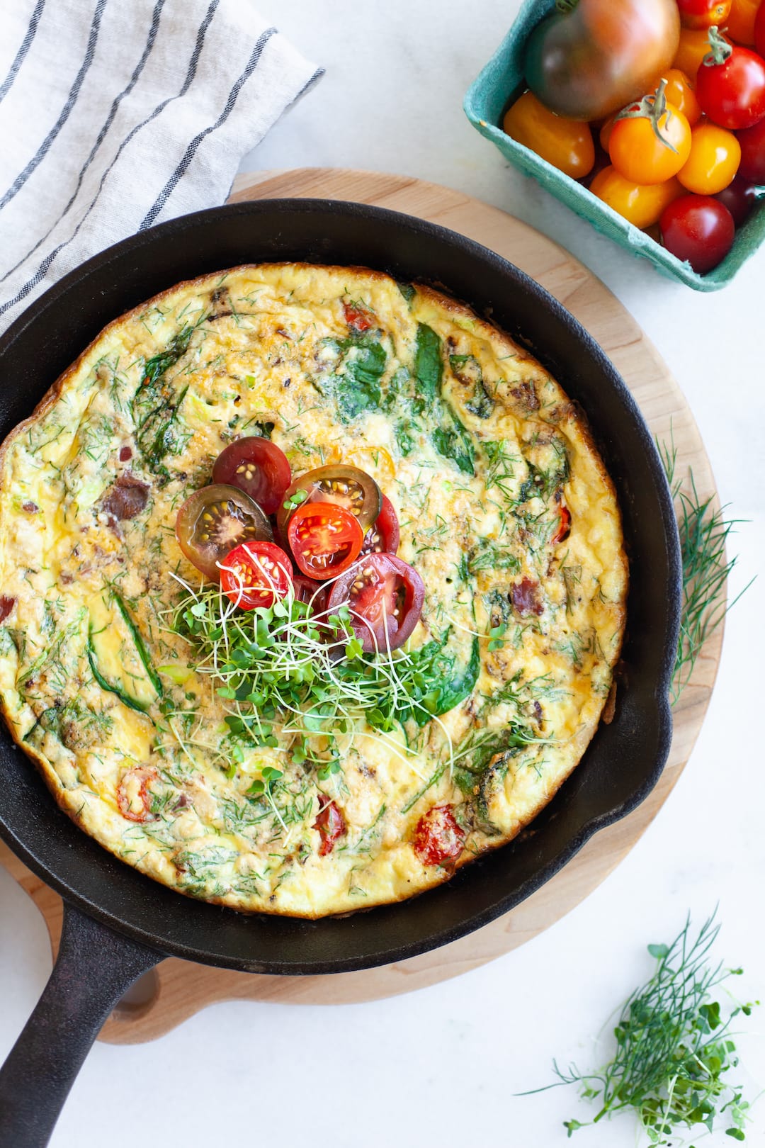 Baked frittata in a black skillet with vegetables