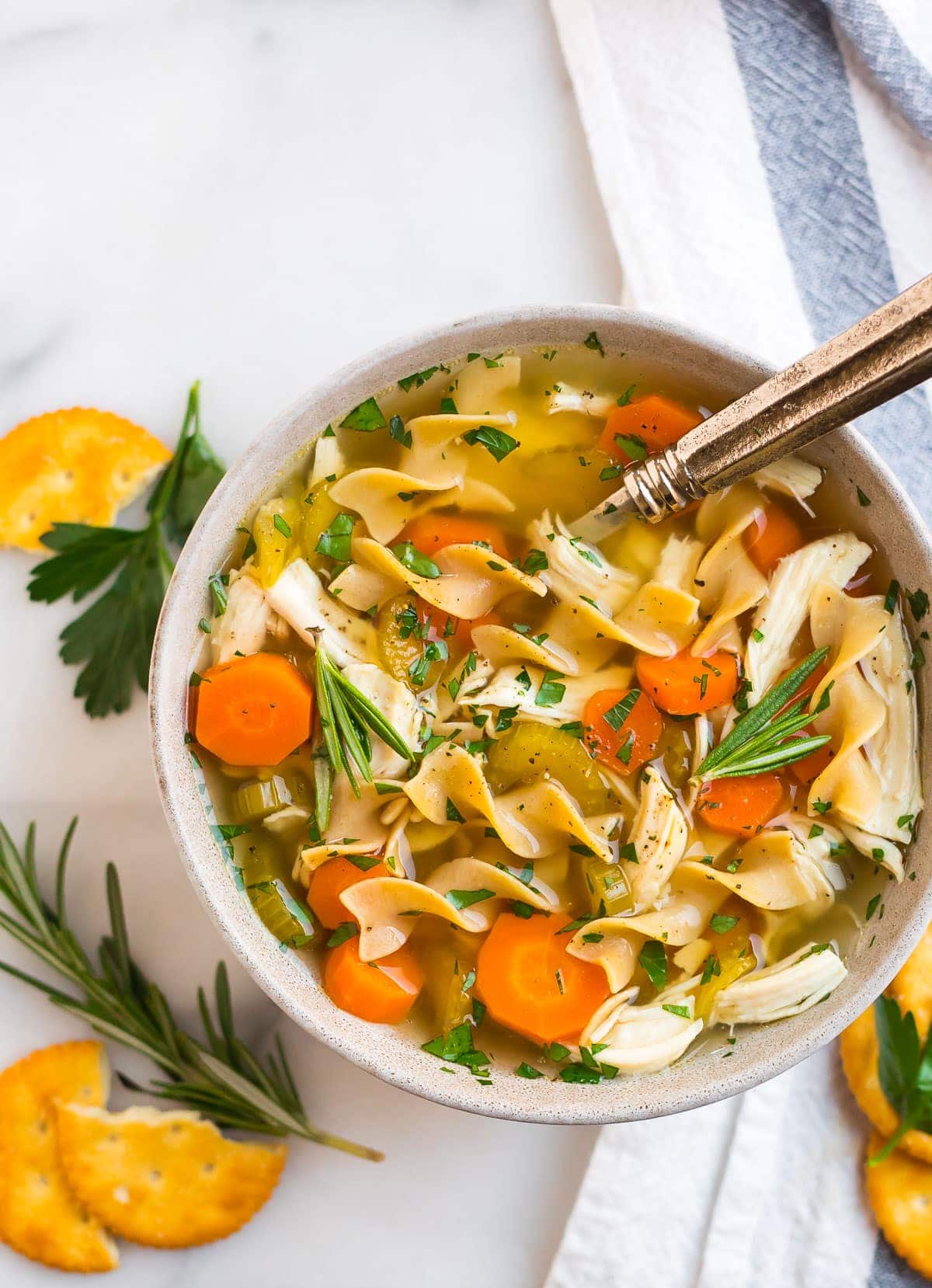 Crockpot chicken noodle soup in a bowl with carrots and herbs
