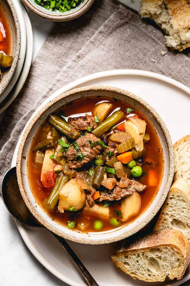 Crockpot Vegetable Beef Soup in a bowl with bread on the side