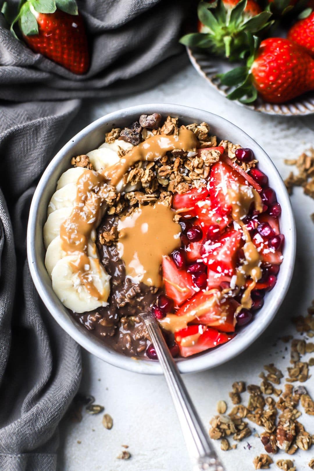Big bowl of chocolate overnight oats topped with nut butter, banana, and berries