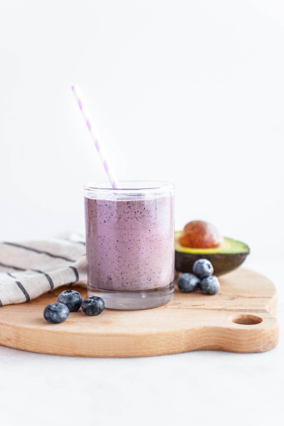 Creamy Blueberry Avocado Smoothie in a glass with a purple straw
