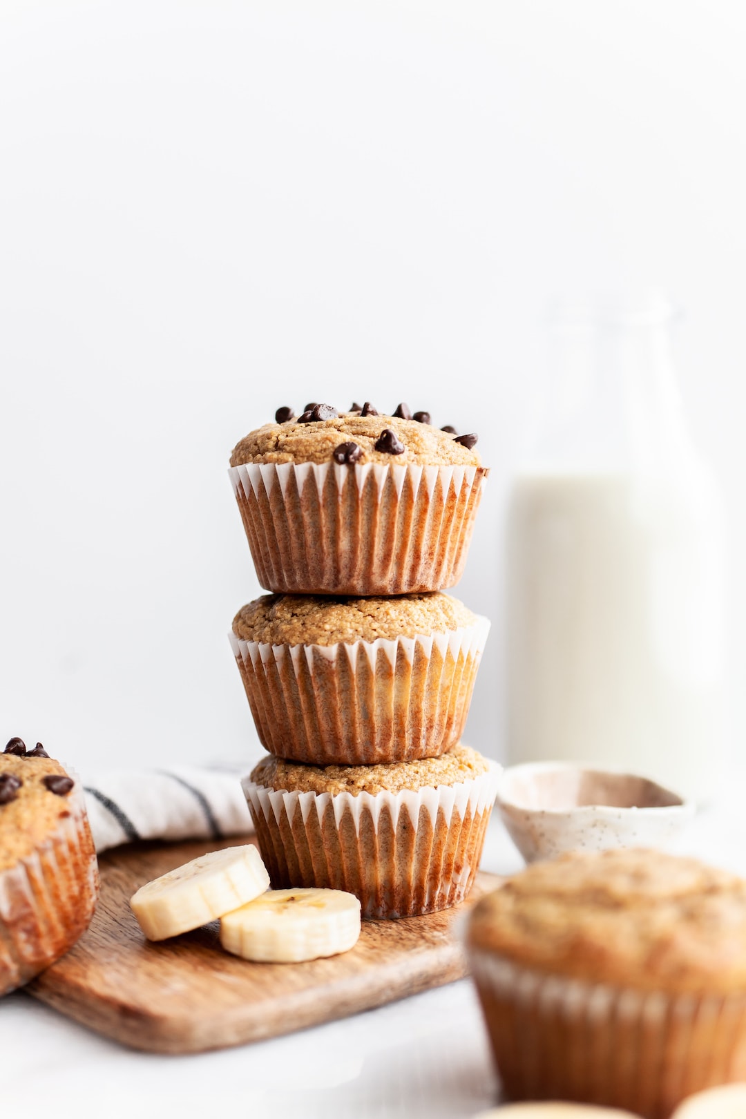 Stack of three Easy Almond Flour Banana Muffins with glass of milk in the background