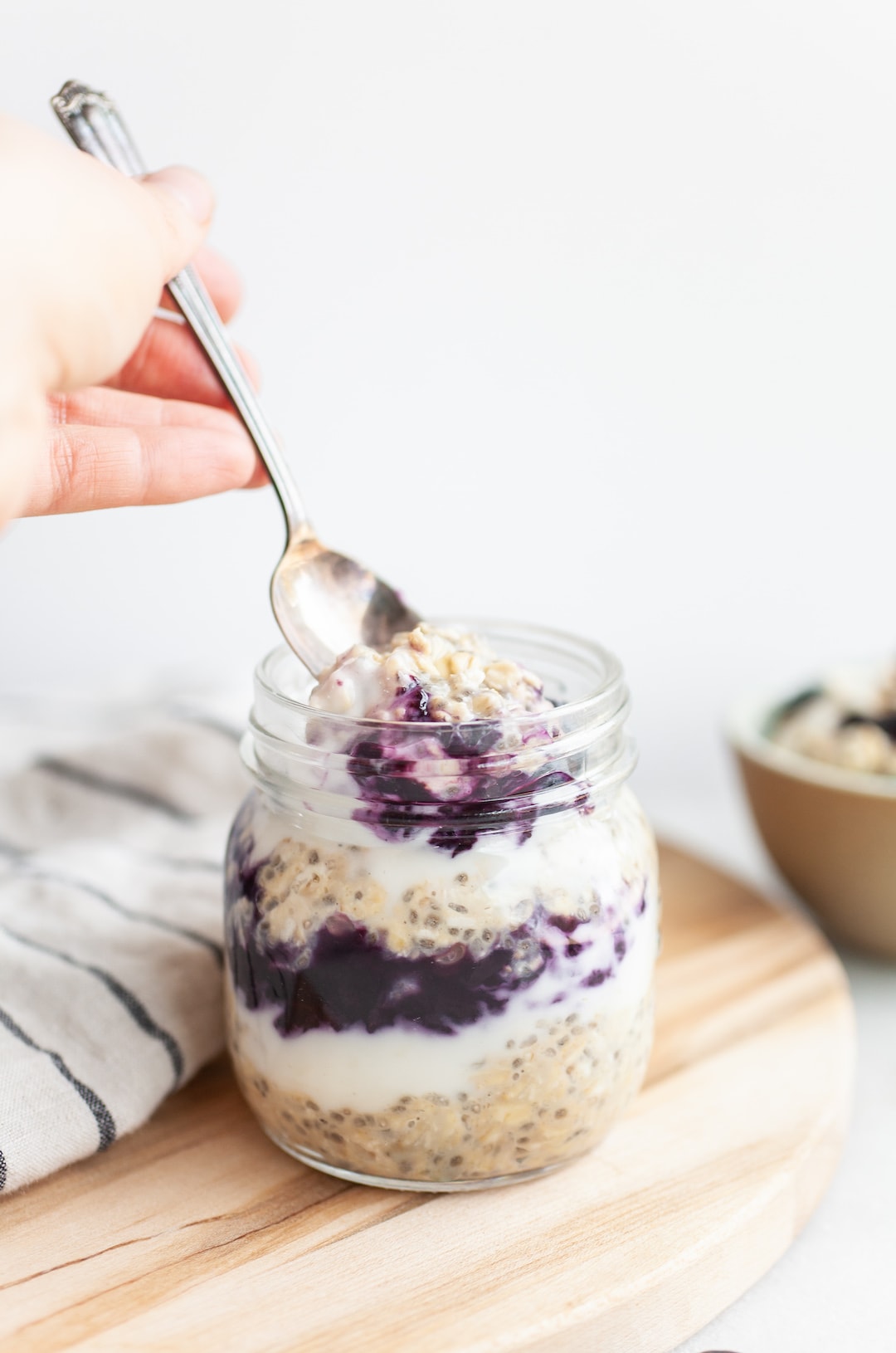 scooping a spoonful of blueberry overnight oats out of a jar