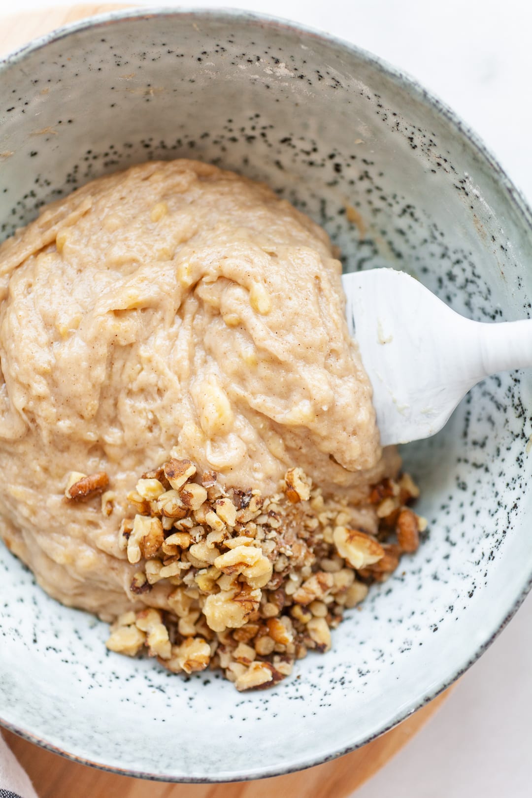 Instant Pot Banana Bread batter in a bowl with walnuts and a white spatula