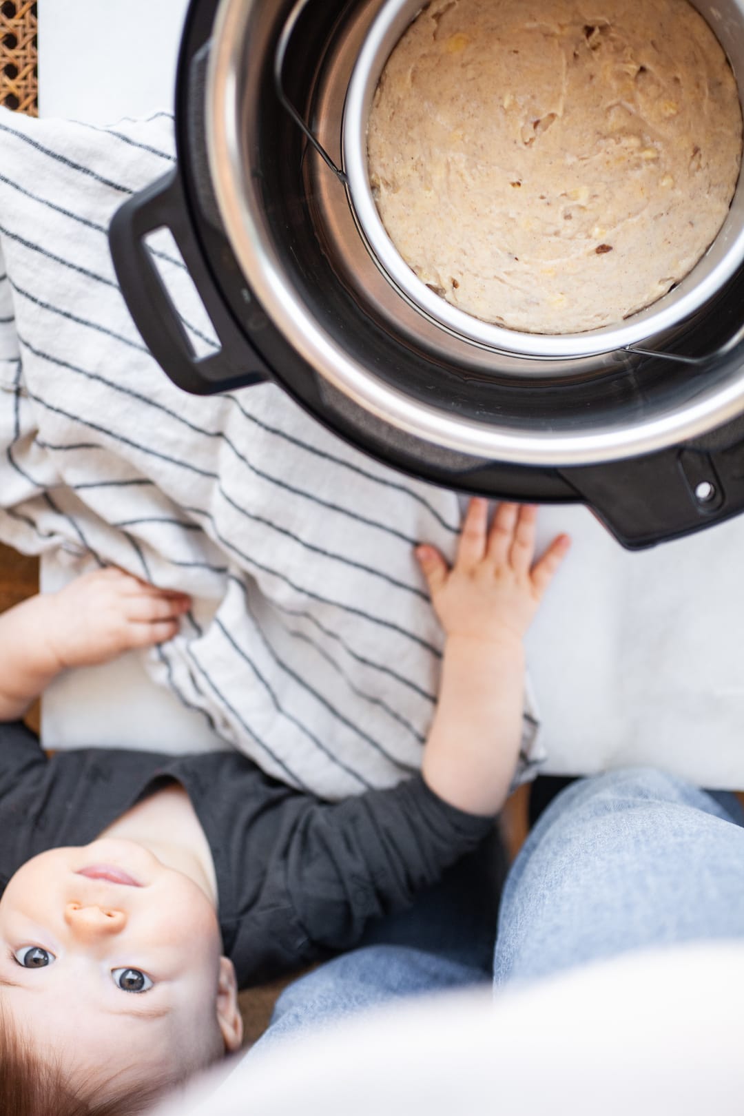 Cake pan sitting inside an instant pot filled with banana bread batter and a small child reaching for it