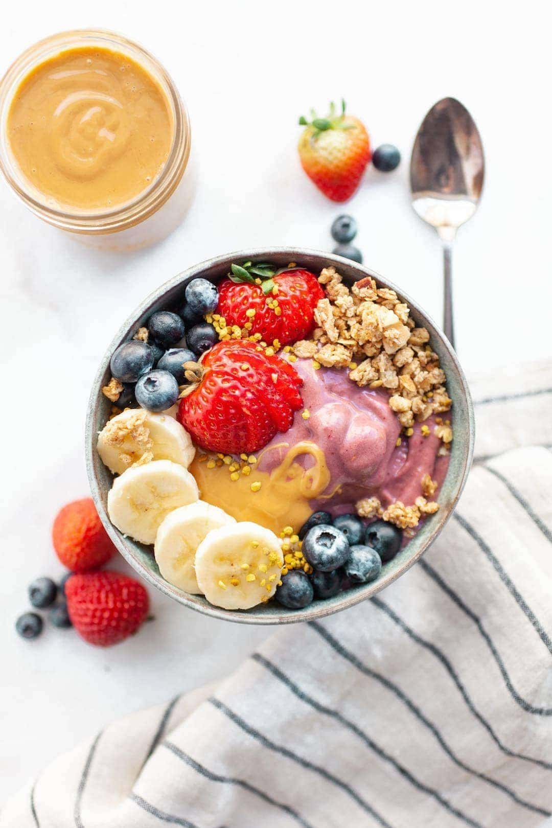 peanut butter acai bowl topped with berries, banana, and bee pollen
