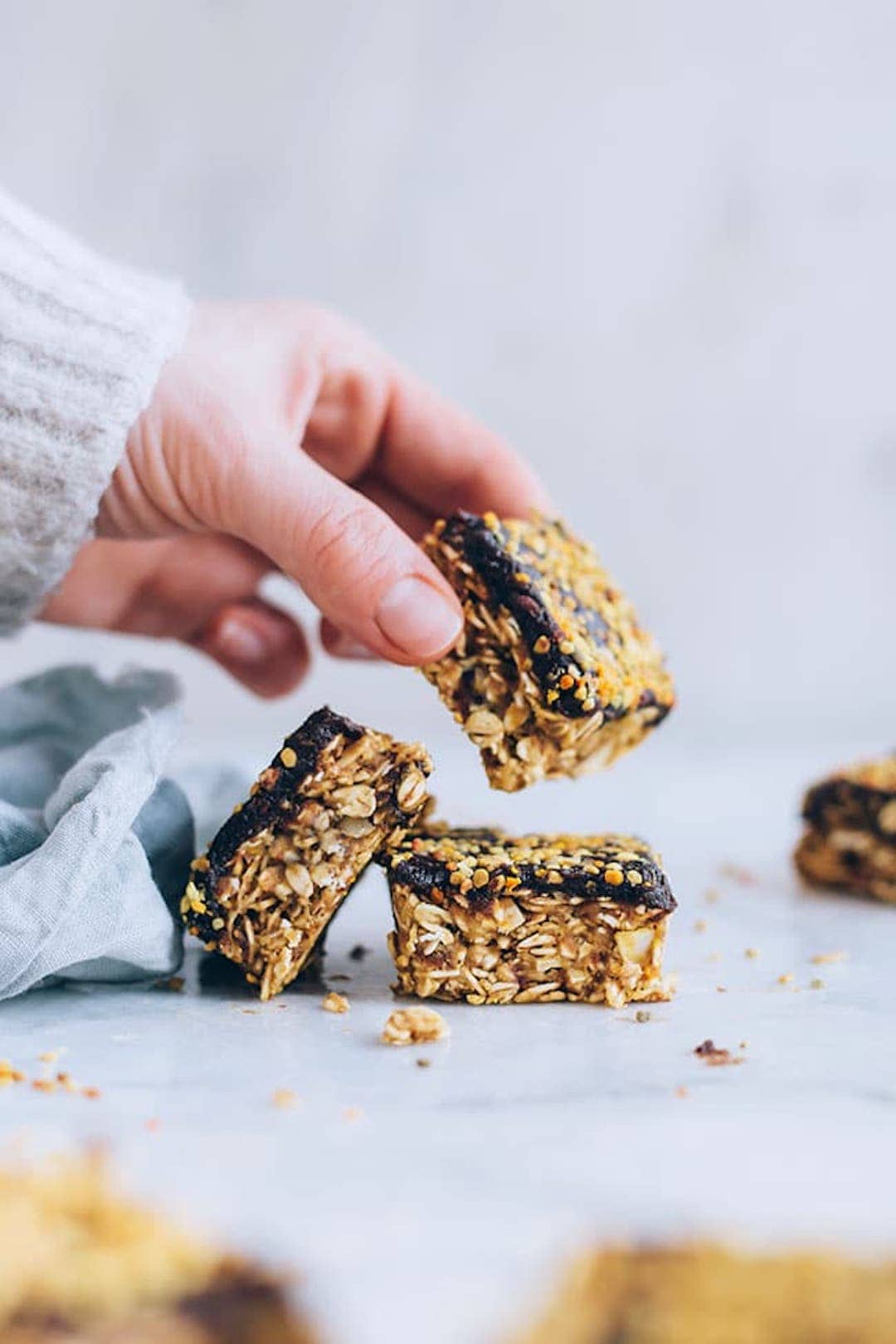 peanut butter granola bars topped with bee pollen and one being picked up by a hand