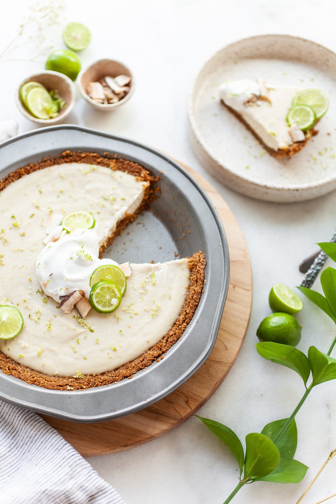 Vegan Key Lime Pie on a wood board with a slice taken out and the slice on a plate beside the pie