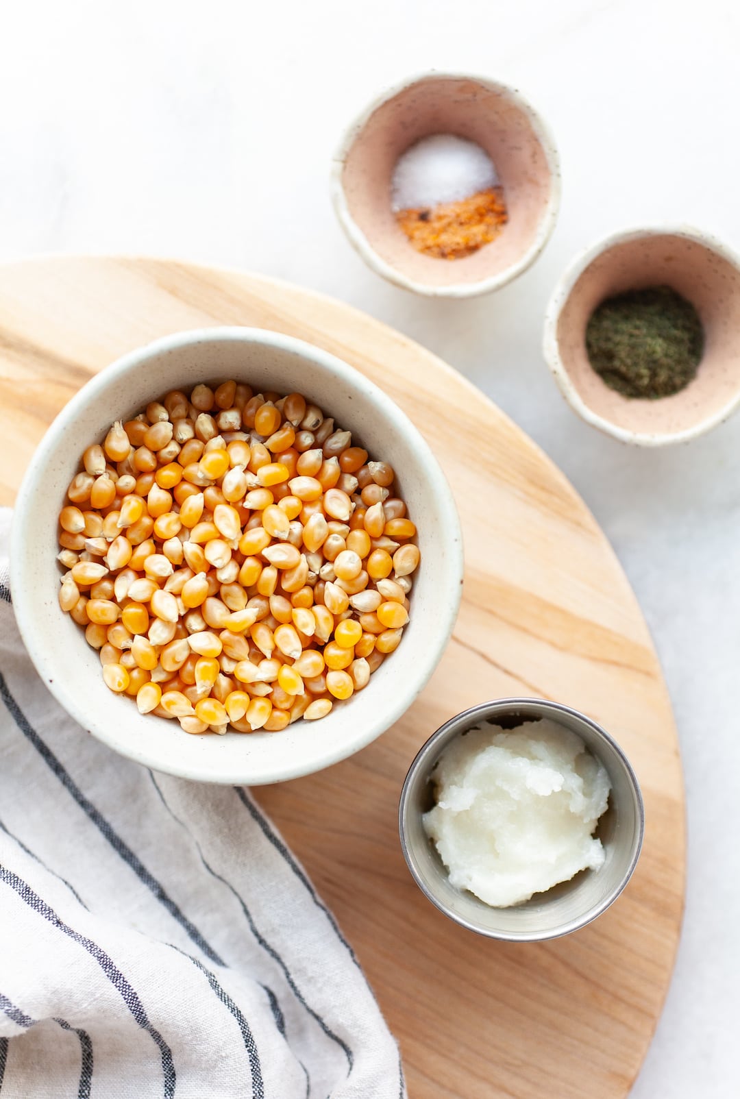 instant pot popcorn ingredients on a wooden board - popcorn kernels, coconut oil, seasonings
