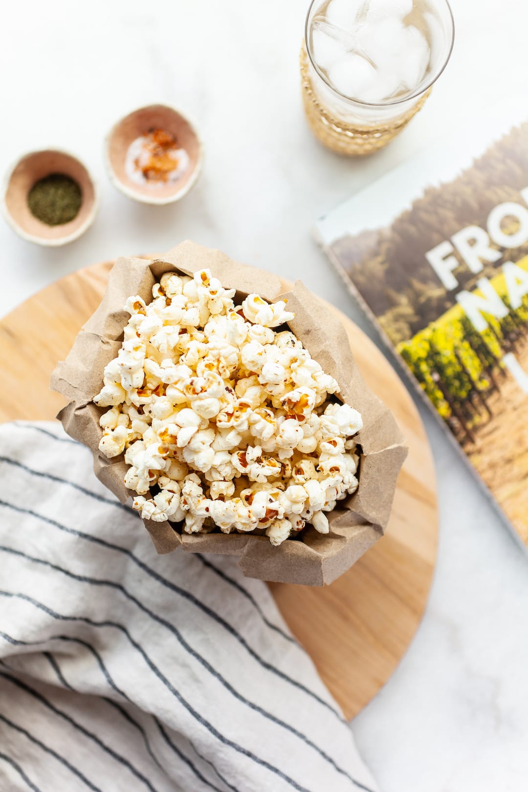 instant pot popcorn in a paper bag on a wooden board with a book beside it for styling