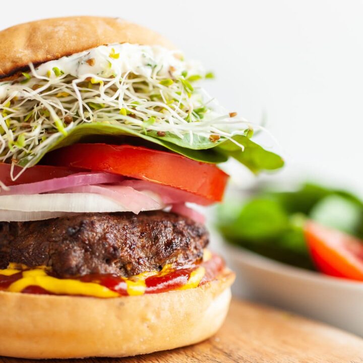 Close up of Air fryer burger with sprouts, lettuce, tomatoes, ketchup and mustard