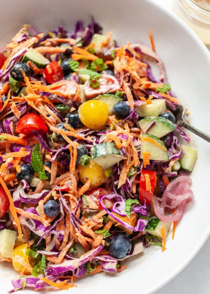 close up of bowl of rainbow salad tossed with tahini dressing