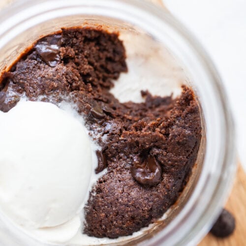 close up of a vegan mug brownie in a jar with a scoop taken out