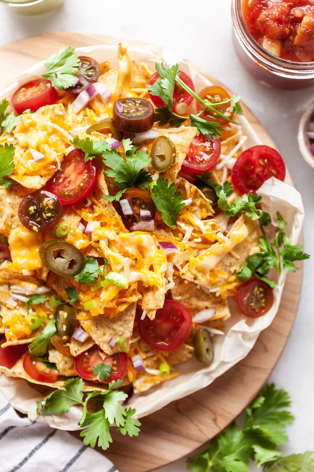 Close up of Air Fryer Nachos on a plate covered with tomatoes, cilantro, onion, jalapeños, cheese, and guacamole