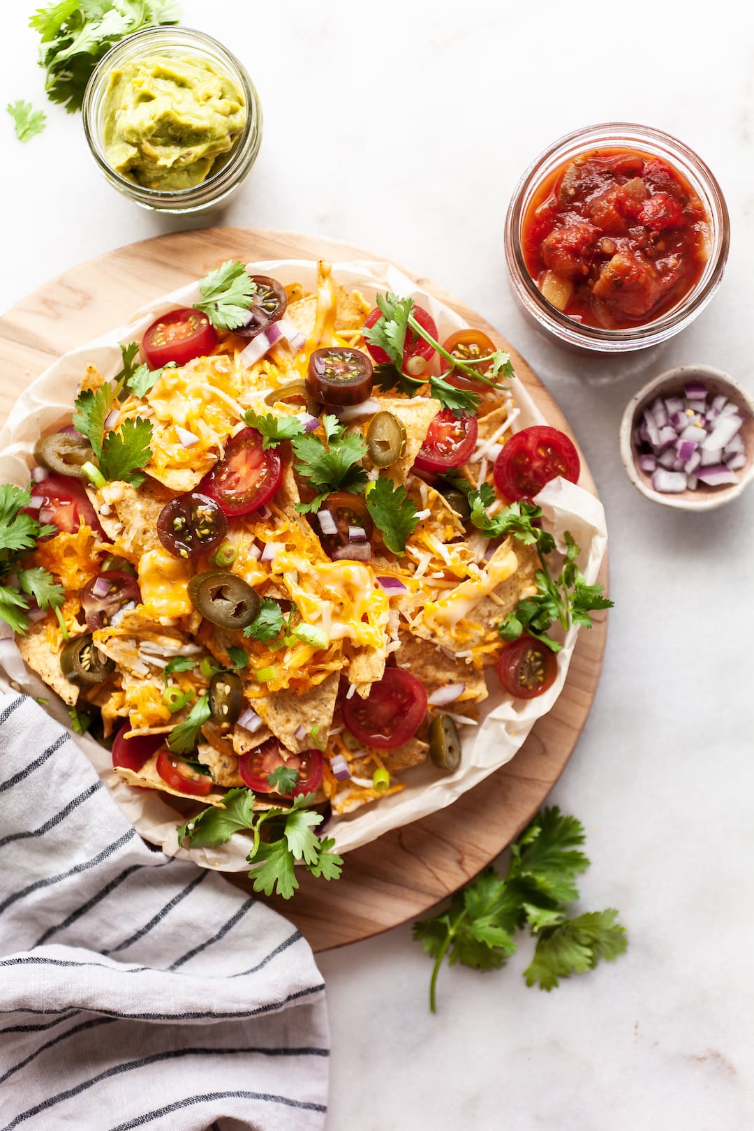 Loaded air fryer nachos on a wood platter with salsa and guacamole on the side