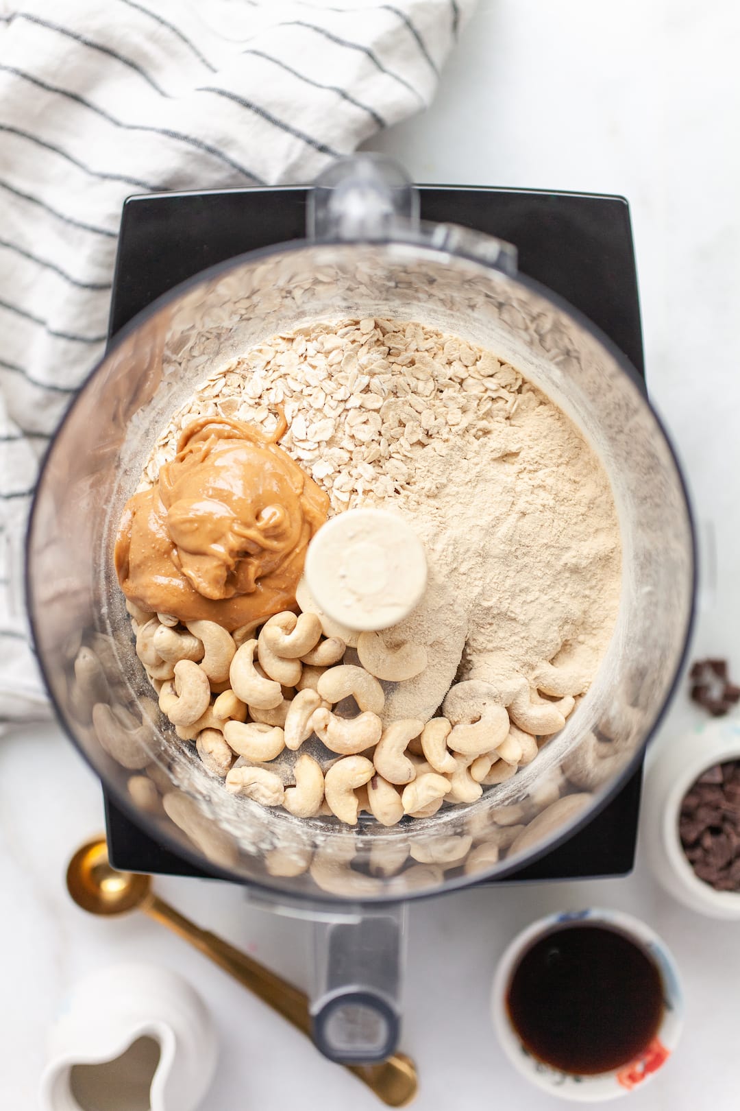 ingredients for protein cookie dough in a food processor - cashews, peanut butter, rolled oats, protein powder