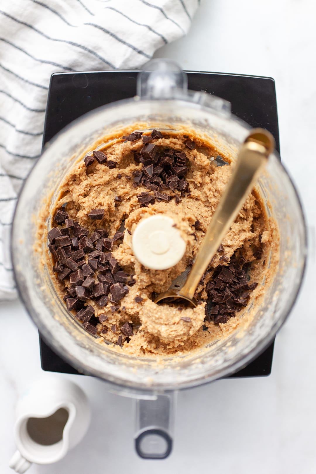 protein cookie dough batter in a food processor with dark chocolate chunks