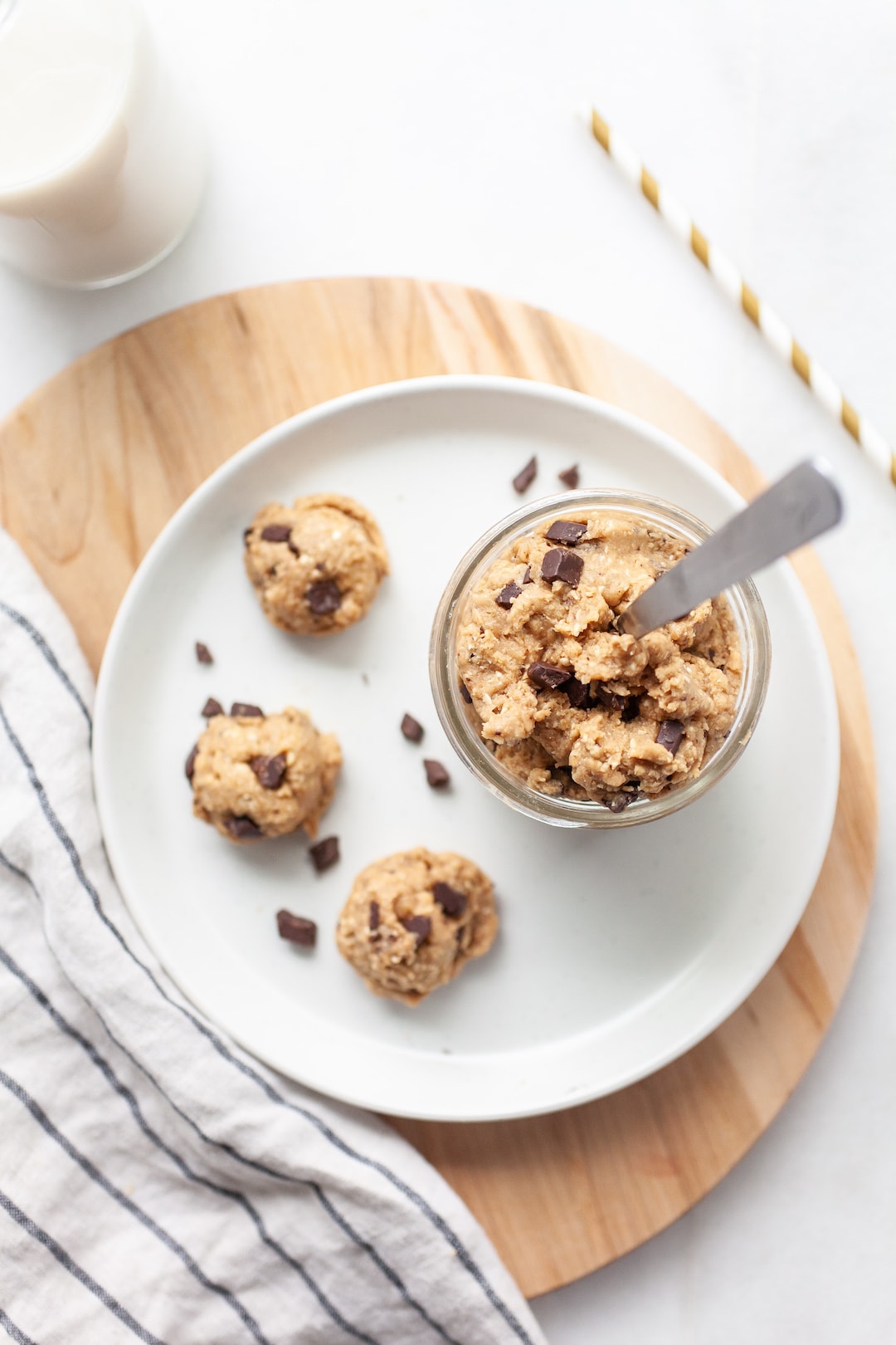 protein cookie dough on a white plate arranged in balls and some in a glass jar with a spoon