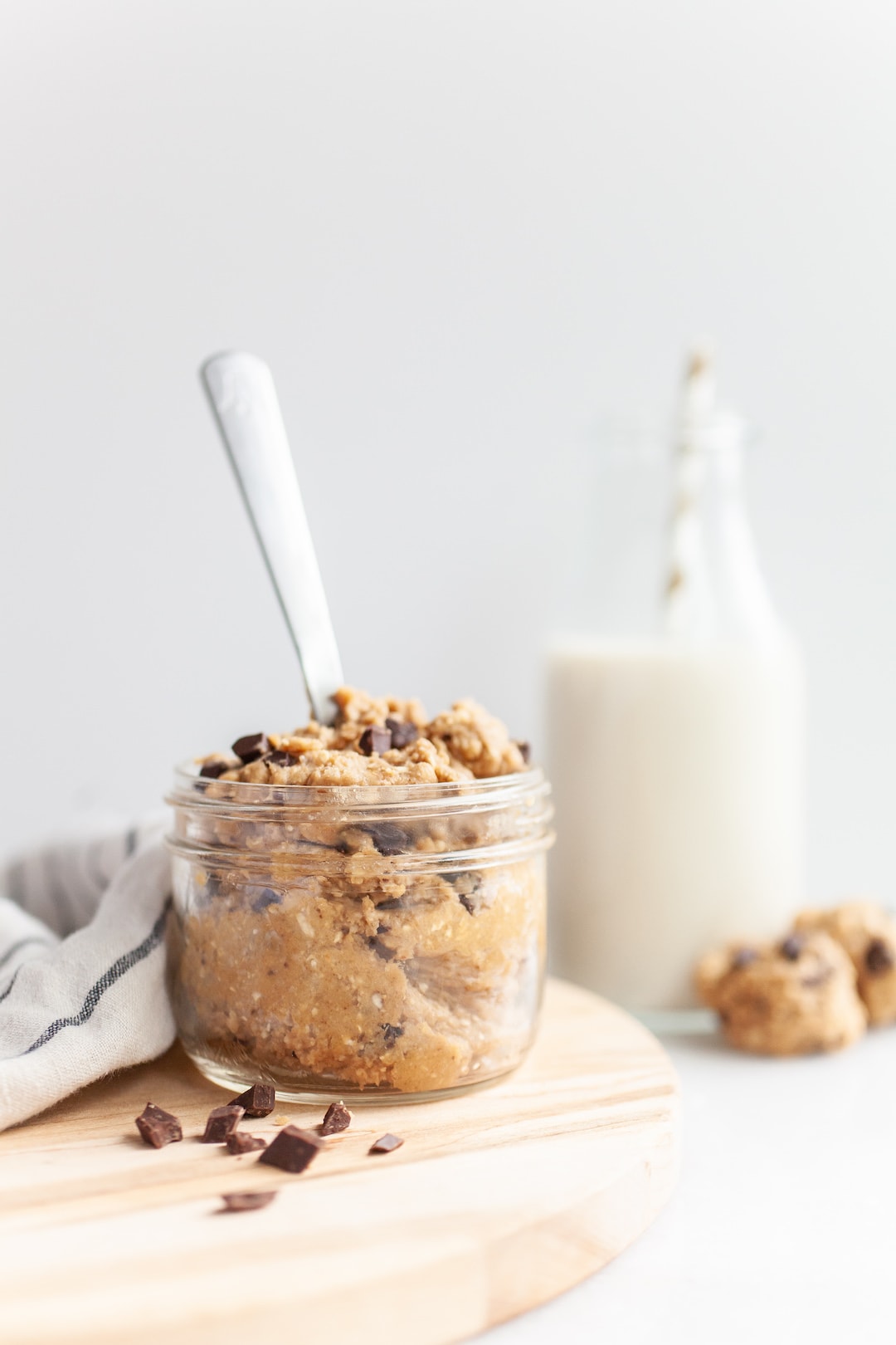 side view of a jar of protein cookie dough with a spoon in it