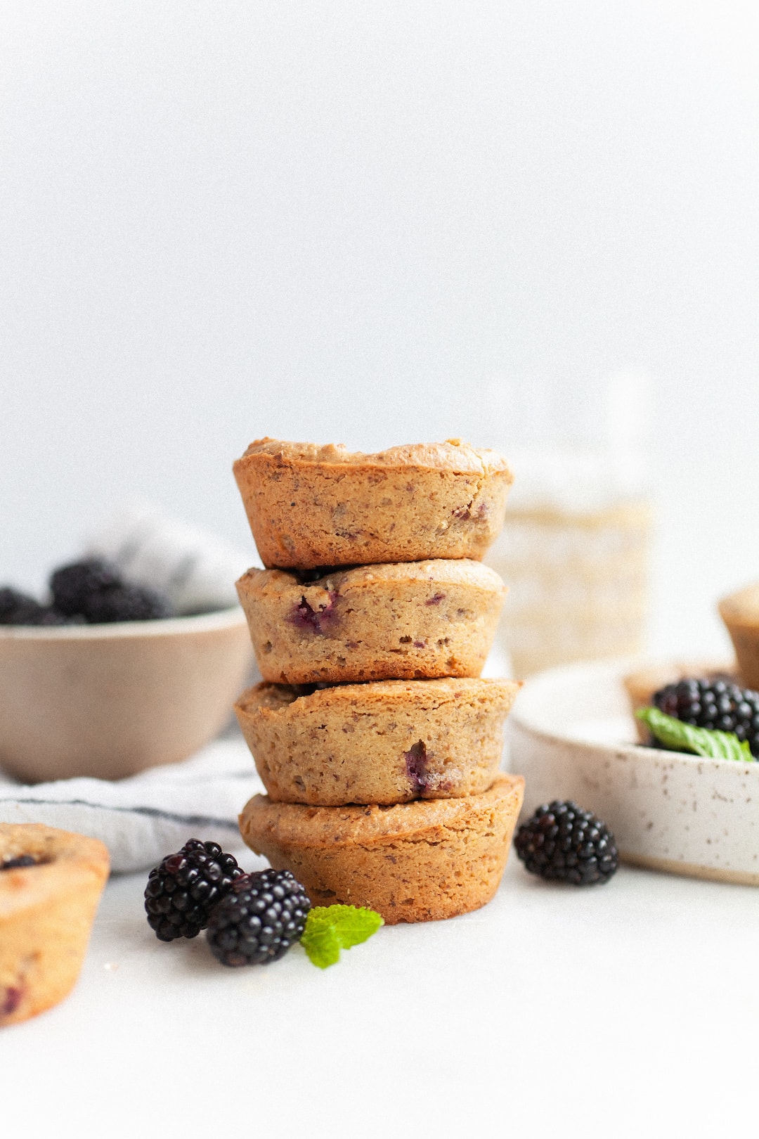 Stack of 4 vegan blackberry muffins with blackberries surrounding