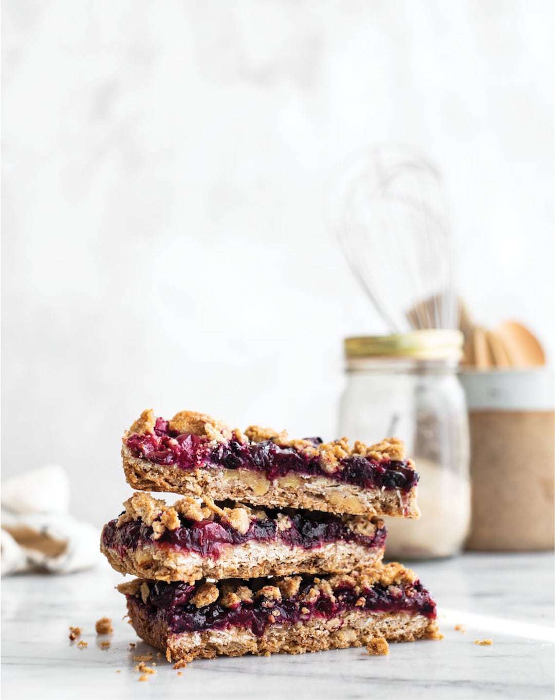 three fruit crumble bars stacked on a marble board