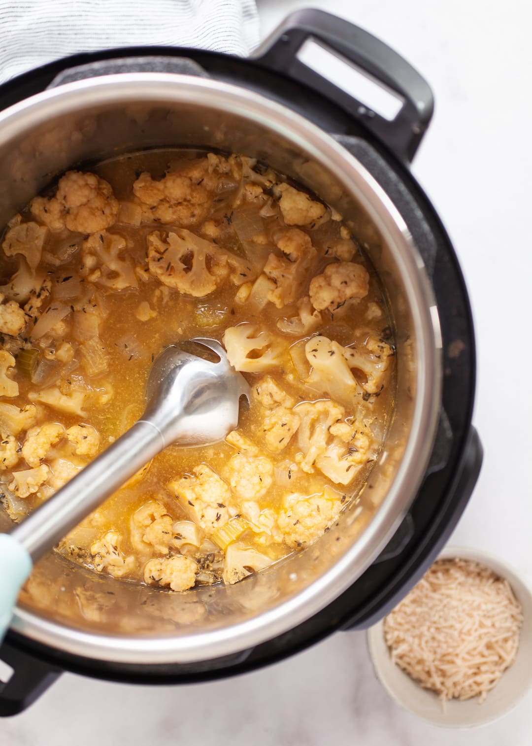 image of cauliflower soup in an instant pot with an immersion blender