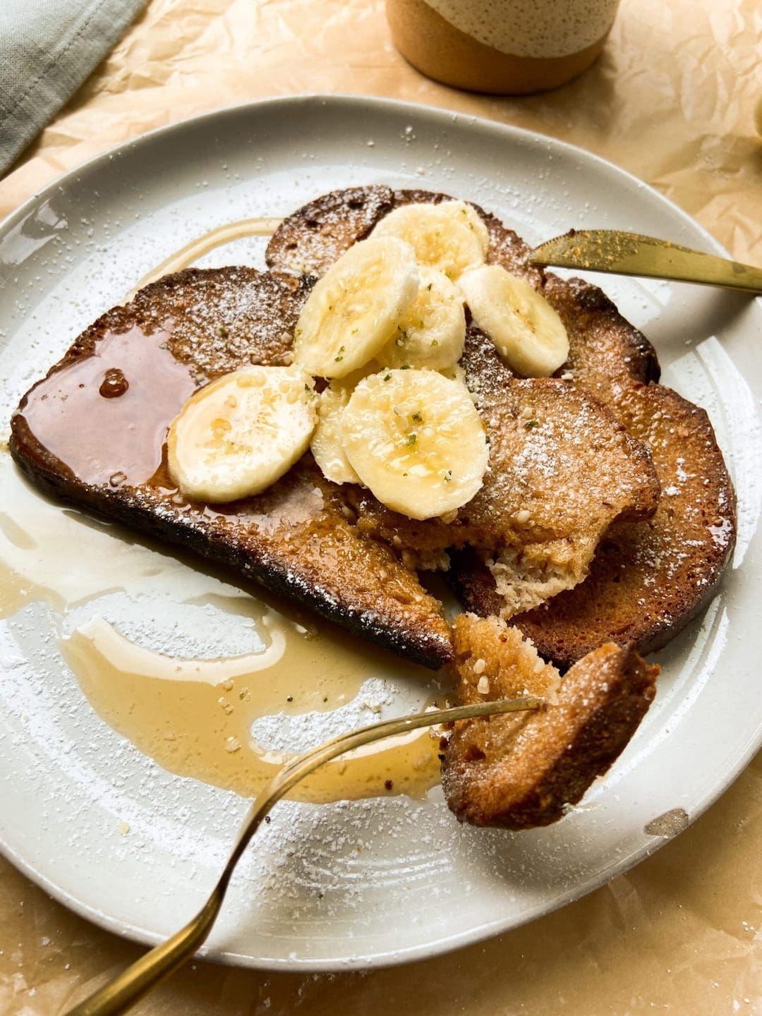 image of a white plate topped with air fryer French toast with syrup and sliced bananas